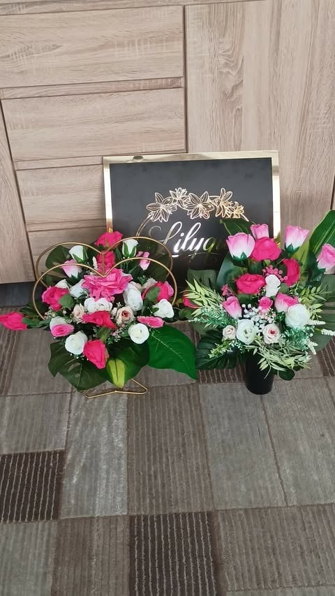 Two floral arrangements with pink, white, and red flowers displayed on a tile floor next to a chalkboard sign