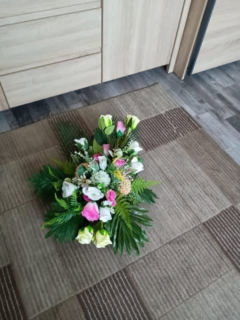 Colorful flower arrangement with pink, white, and purple blooms on a striped doormat inside an entryway