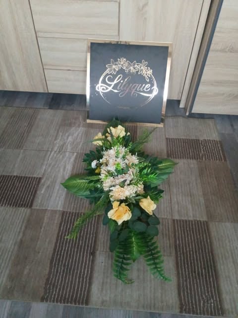 Floral arrangement with white and yellow flowers and green foliage beneath a Lumina sign in an entryway
