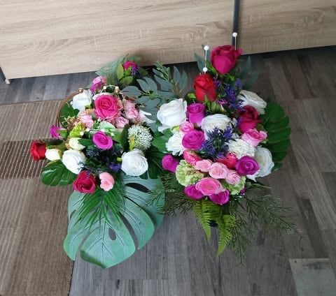 Vibrant floral arrangement with pink, white, and red flowers in a green vase on a wood floor