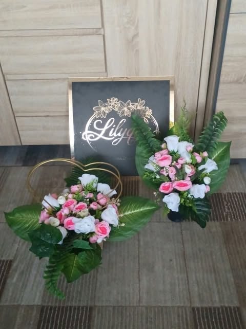 Two floral arrangements with pink and white flowers beside a chalkboard sign reading Lily in an event display