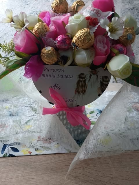 A decorative flower bouquet with pink and white flowers, gold ornaments, and a pink ribbon, featuring a personalized message card dated 2026
