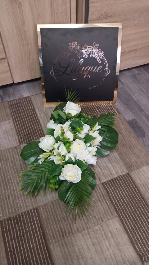 Chalkboard wedding sign with La venue text above white flower arrangement with green foliage on wooden floor