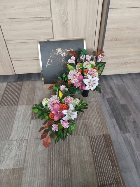 Vibrant floral arrangement with pink and white flowers next to a dark chalkboard sign on a gray tile floor