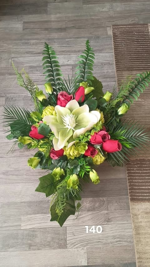 Vibrant floral arrangement with white lilies, pink roses, yellow carnations, and green ferns on wooden floor