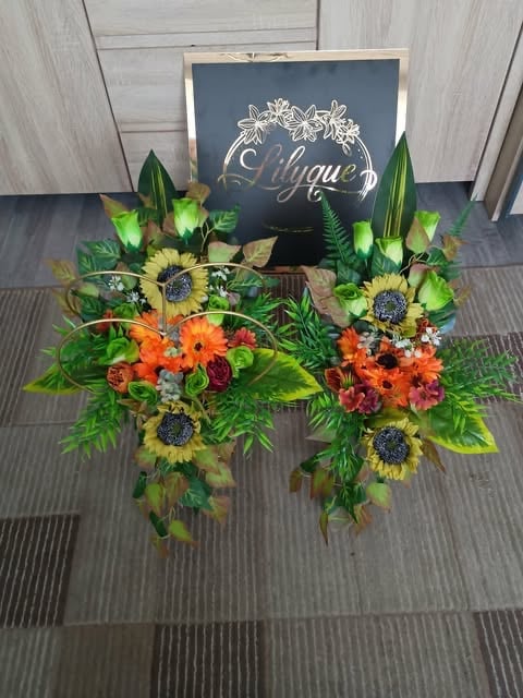 Wedding welcome display with chalkboard sign, sunflowers, gerbera daisies, and greenery arrangements on textured floor