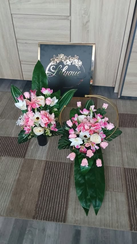 Two floral arrangements with pink and white flowers in glass vases beside a black chalkboard sign reading Elegance against light wood paneling.