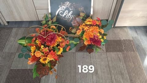 Floral display with orange and pink flowers at apartment entrance, number 189 visible on mat