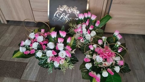 Three lush floral arrangements with pink, white, and red flowers and greenery displayed on wooden flooring.