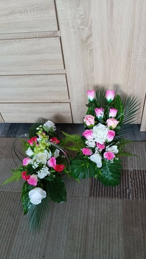 Two floral arrangements on gray flooring with light wood wall background. Left arrangement features pink, red, and white flowers. Right arrangement displays pink and white roses with greenery.