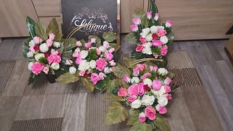 Display of four pink and white floral arrangements with chalkboard sign reading Unique on wooden floor