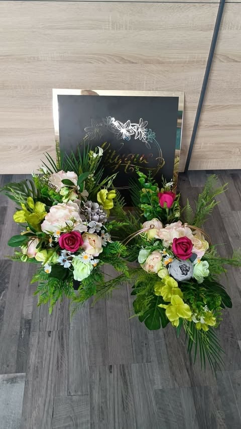 Floral arrangement display with white, pink, and red flowers alongside a black chalkboard sign on wooden flooring