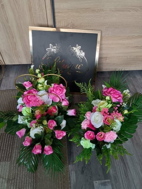 Two vibrant floral arrangements with pink roses and white flowers beside a chalkboard sign with decorative elements