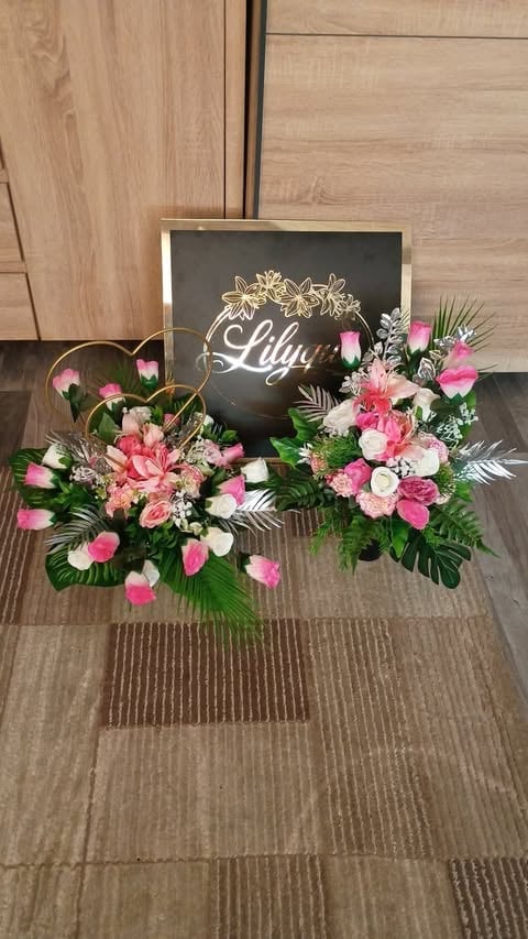 Floral arrangement with pink and white flowers displayed next to a chalkboard sign reading Lily on wooden flooring.
