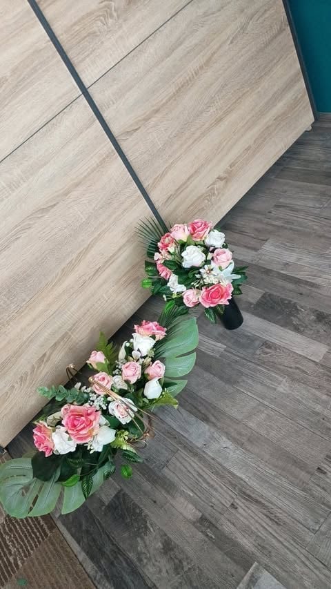 Floral arrangement with pink and white flowers trailing along wooden flooring in an interior space