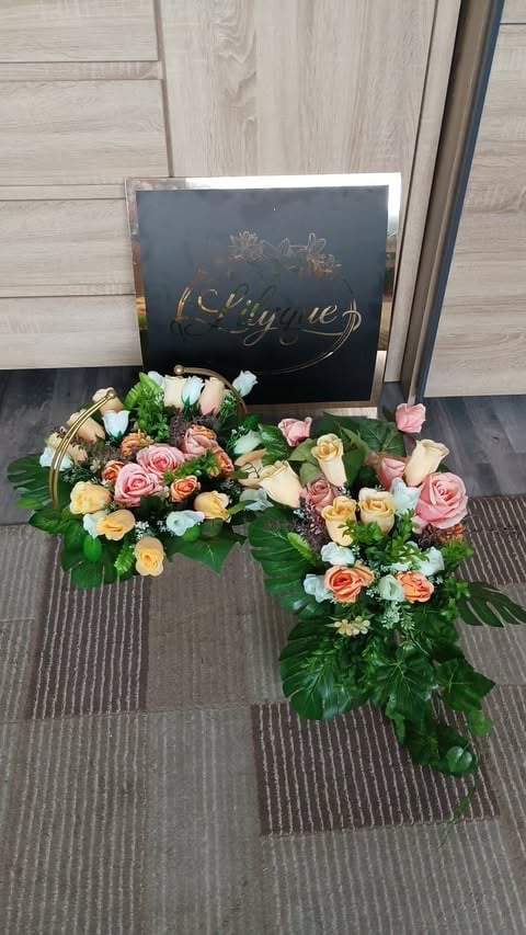 Elegant flower arrangement with pastel roses, carnations, and greenery displayed in front of a black Ubuyged branded box on light wood flooring