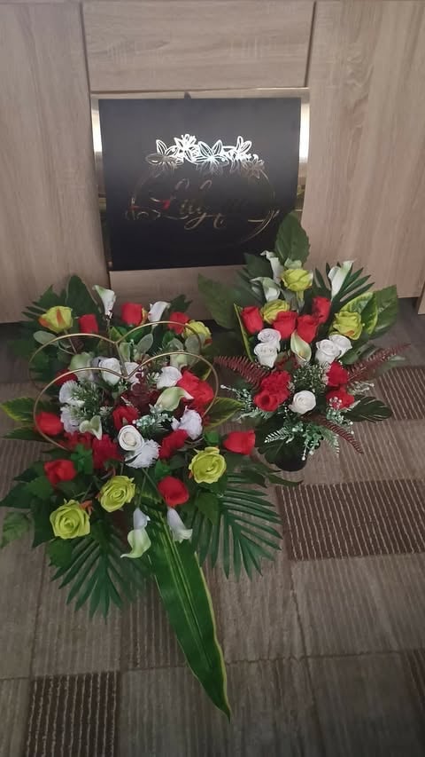 Floral arrangements with red, white, and yellow flowers displayed on a dark chalkboard sign with decorative frame