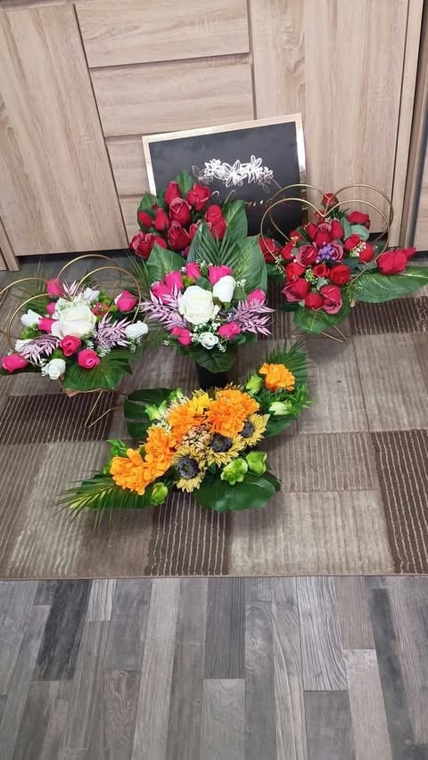 Four colorful flower arrangements displayed on wooden flooring, featuring red roses, pink and white flowers, and yellow chrysanthemums with greenery