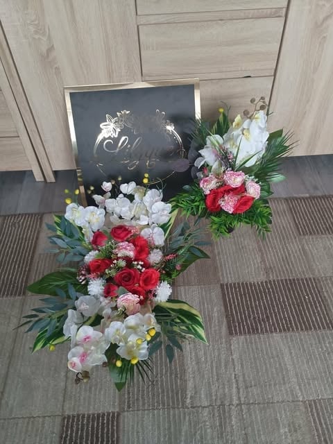 Two floral bouquet arrangements with red, white, and pink flowers displayed on gray tile flooring with a dark chalkboard sign in the background