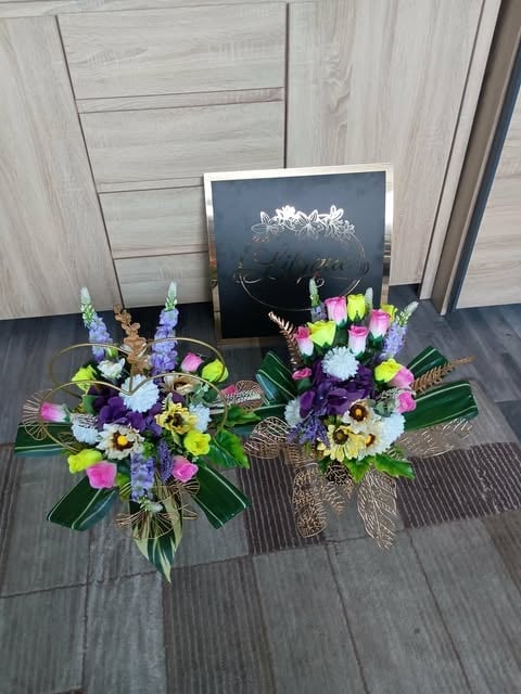 Two colorful flower arrangements with purple, pink, yellow, and white blooms next to a chalkboard sign on wooden flooring