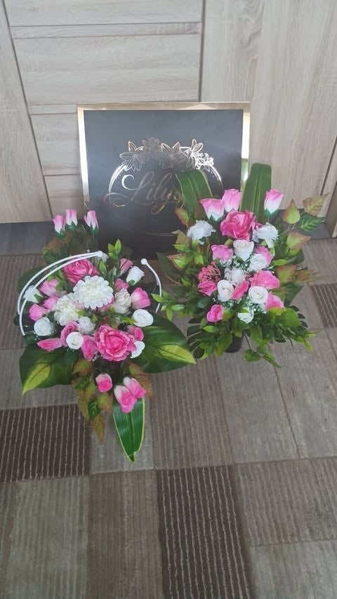 Floral arrangement with pink and white flowers in vases behind a chalkboard sign on gray wood floor