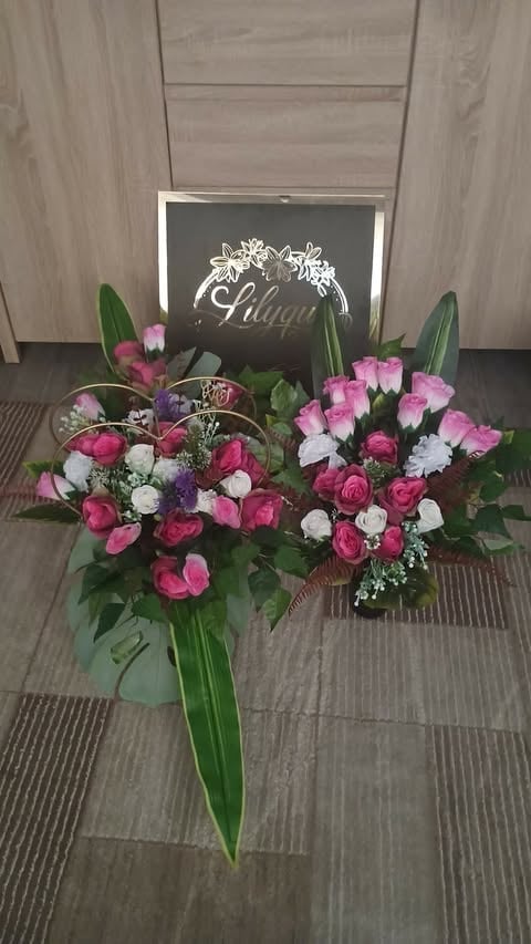 Elegant floral arrangement with pink and white roses and carnations in a vase with green foliage, displayed next to a black Chloe branded sign on wooden flooring