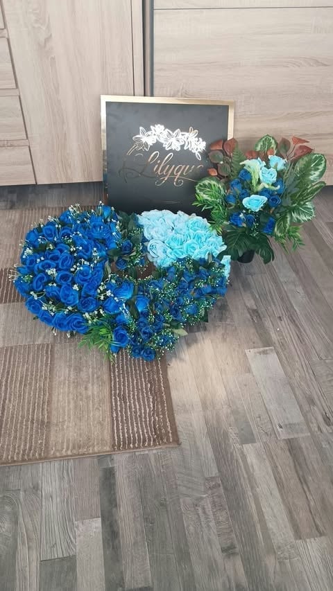 Blue and light blue flower heart-shaped arrangement on wooden floor with a chalkboard sign behind it