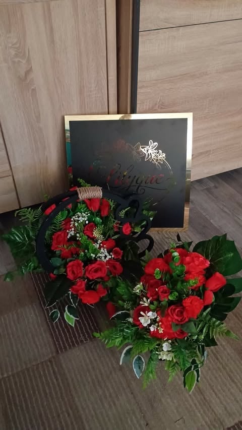 Red rose flower arrangement with white babys breath and green foliage beside a black framed chalkboard on wooden floor