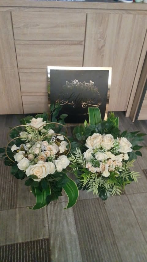 Two bridal bouquets with white and peach roses and green foliage next to a black chalkboard sign on wooden floor