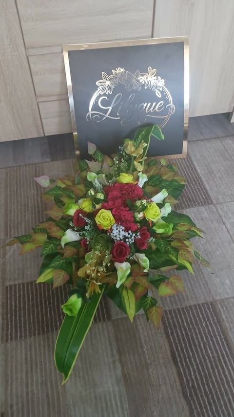 Floral arrangement with red and yellow roses, white flowers, and green foliage beneath a chalkboard sign that reads Love with decorative flourishes
