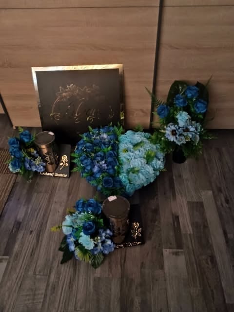 Wedding or event display with blue and white hydrangea arrangements, chalkboard sign, candles, and cardboard backdrop on wooden floor