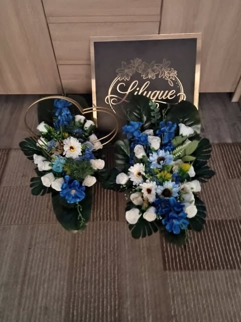 Two floral arrangements with blue, white, and cream flowers next to a wooden sign displaying Lilique branding