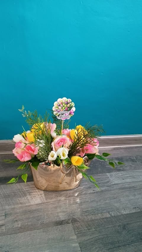 Colorful flower arrangement in a beige fabric pot on gray wood flooring against a bright turquoise wall background